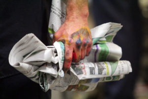 photo of hand holding crumbled newspaper